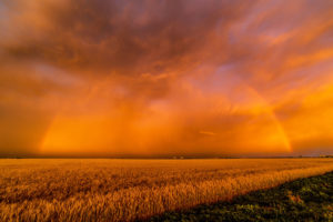 A dust storm with vivid orange sky and rainbow