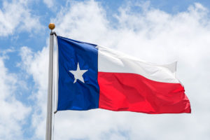 Large Texas (The Lone Star) flag waving on flag pole with cloud